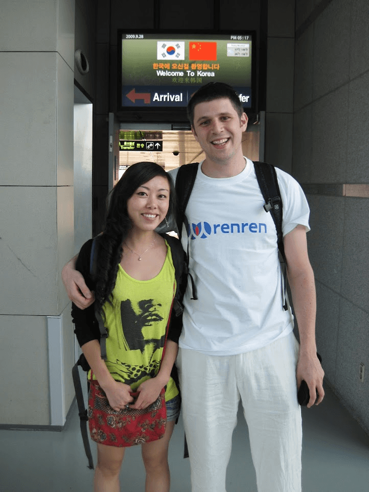 Alex inside an airport with his wife Yan wearing a Renren shirt