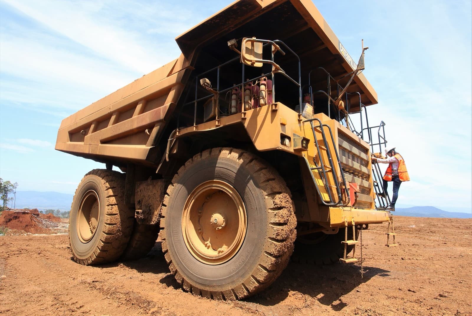 A giant yellow haul truck on red laterite earth at the Sorowako nickel mine in Sulawesi