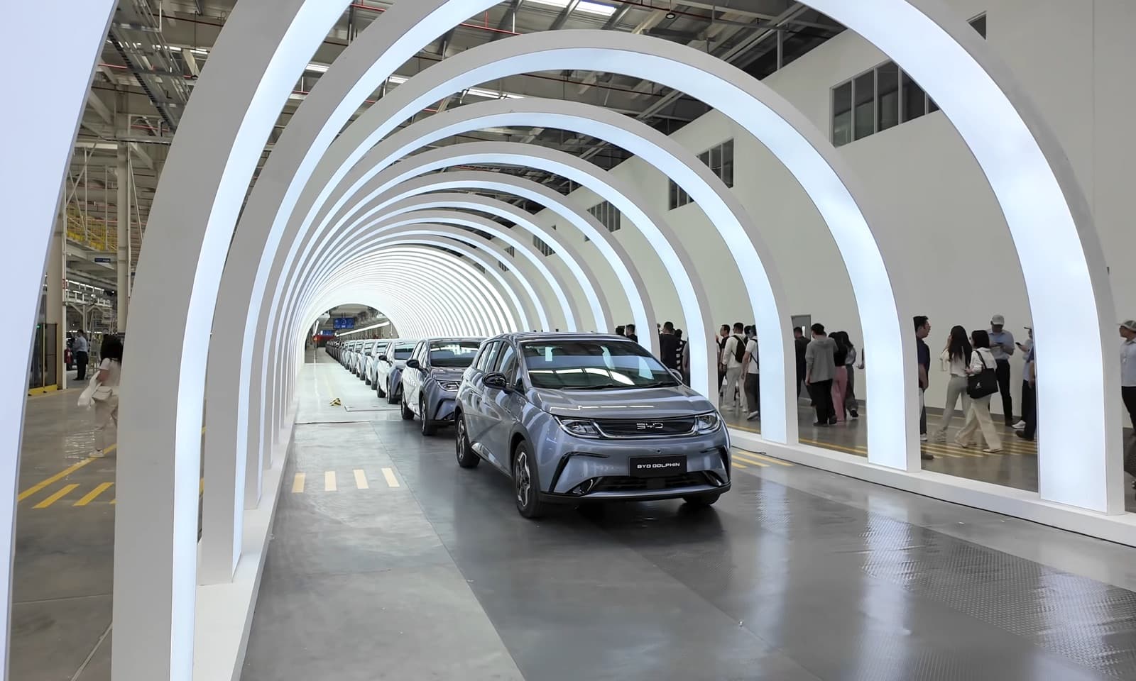 New BYD Dolphin electric cars rolling through illuminated arches at the Rayong plant in Thailand