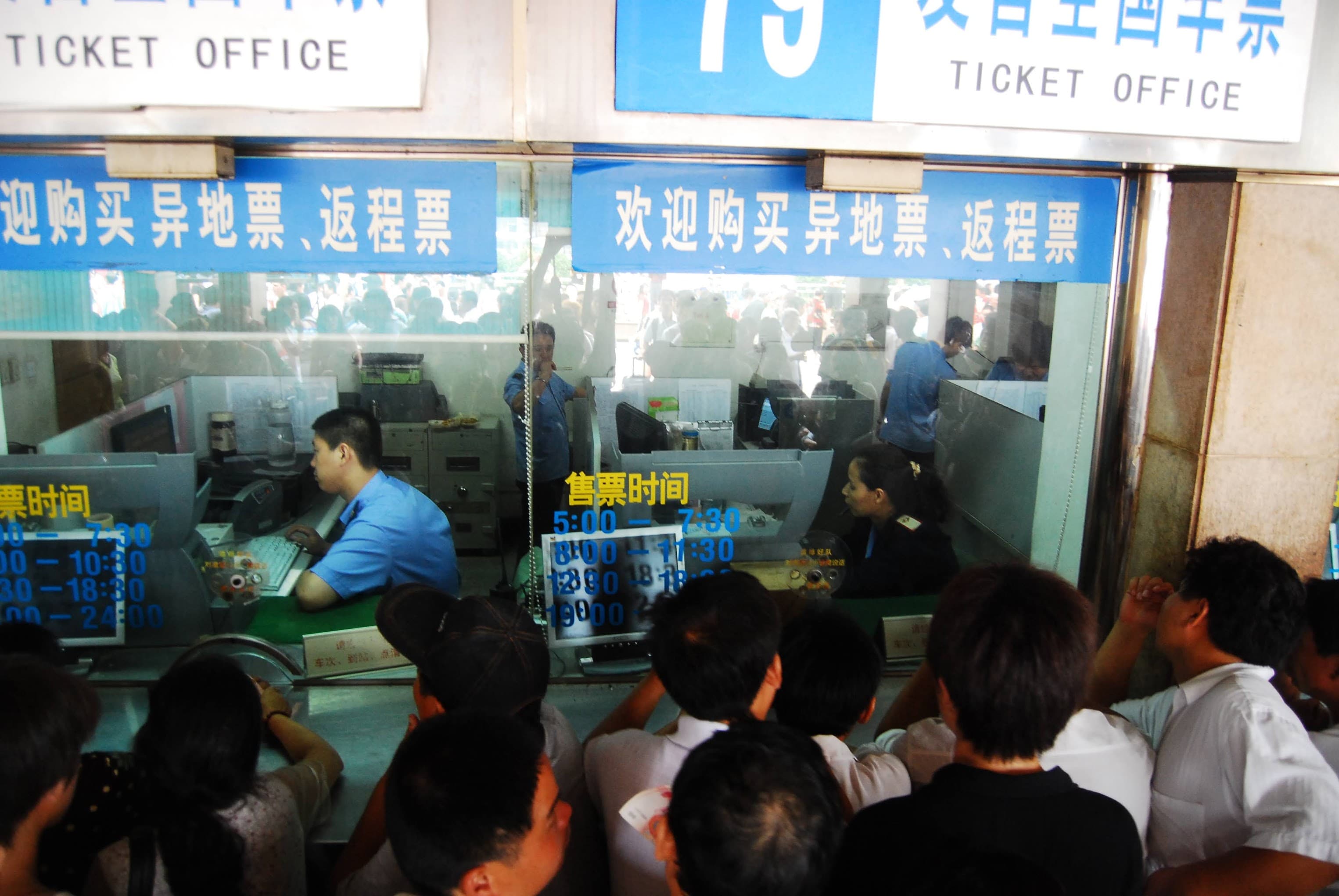 A dense crowd pressed against railway ticket-office windows, Beijing